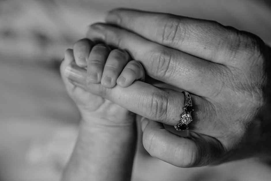 Close-up photo of baby hand holding mother's finger tenderly
