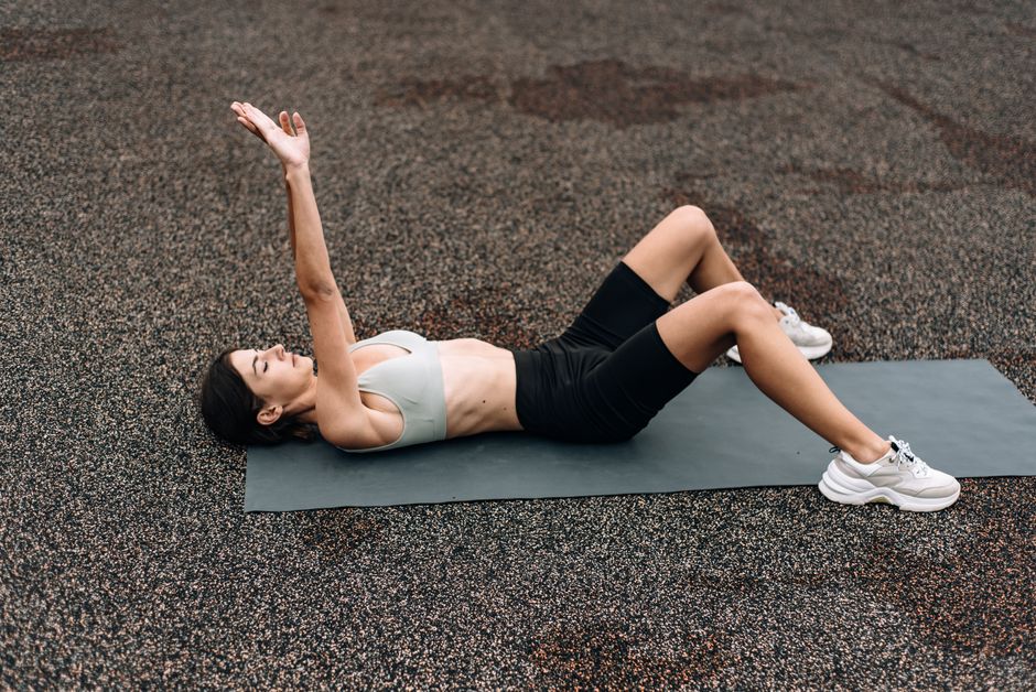 A woman resting and hydrating during a gentle postpartum wellness routine
