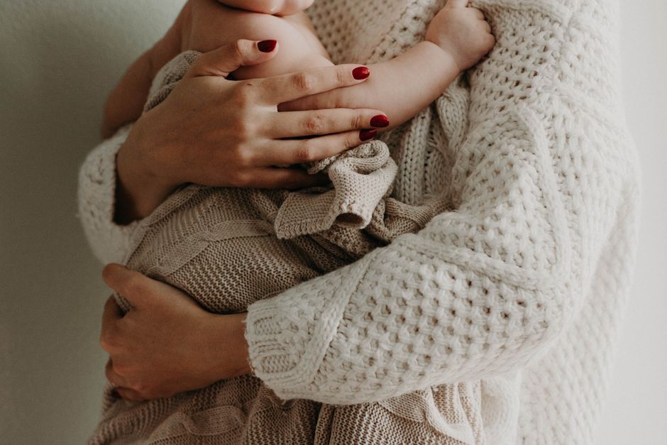 Gentle close-up of a mother holding her newborn baby in a warm, loving embrace