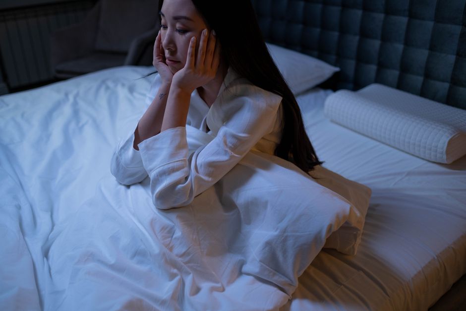 A tired mother in bed at night experiencing postpartum insomnia and deep thought