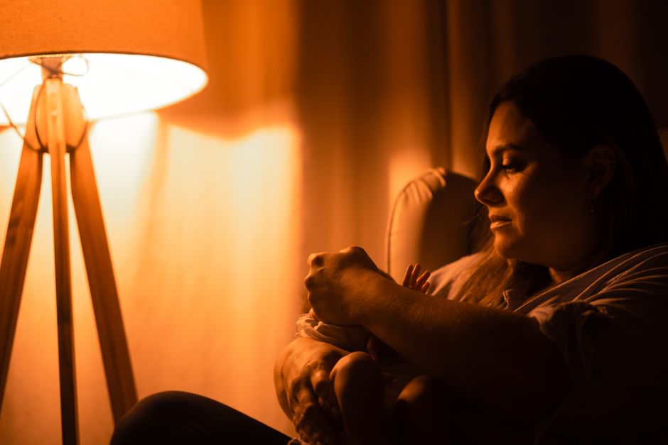 A mother tenderly cradling her infant in soft, warm lamp light