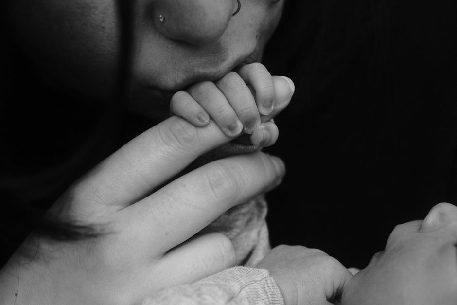 A close-up black and white photo capturing the tender bond between a mother and her baby through hands holding
