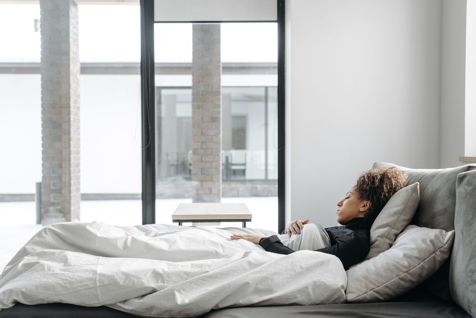 A mother resting comfortably in bed taking a moment for gentle postpartum recovery