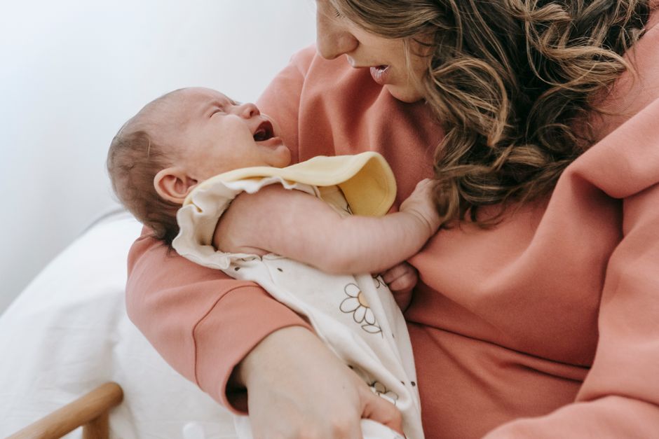 A mother cradling her crying infant while practicing deep calming breaths