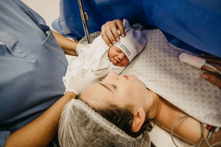 A mother cradling her newborn immediately after childbirth in a hospital setting