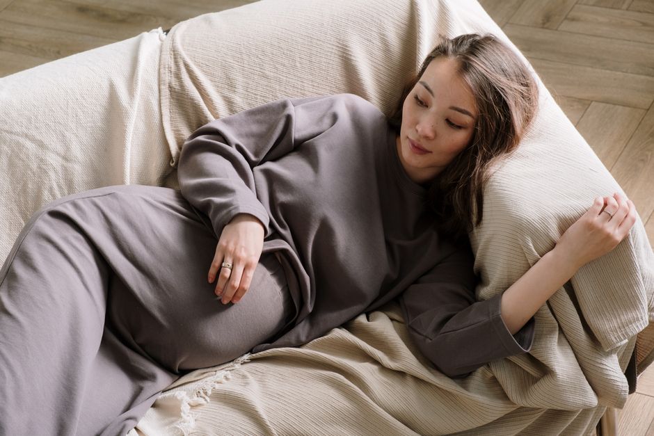 Exhausted mother resting on a couch during postpartum recovery