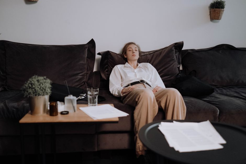 Young mother sitting exhausted on living room sofa