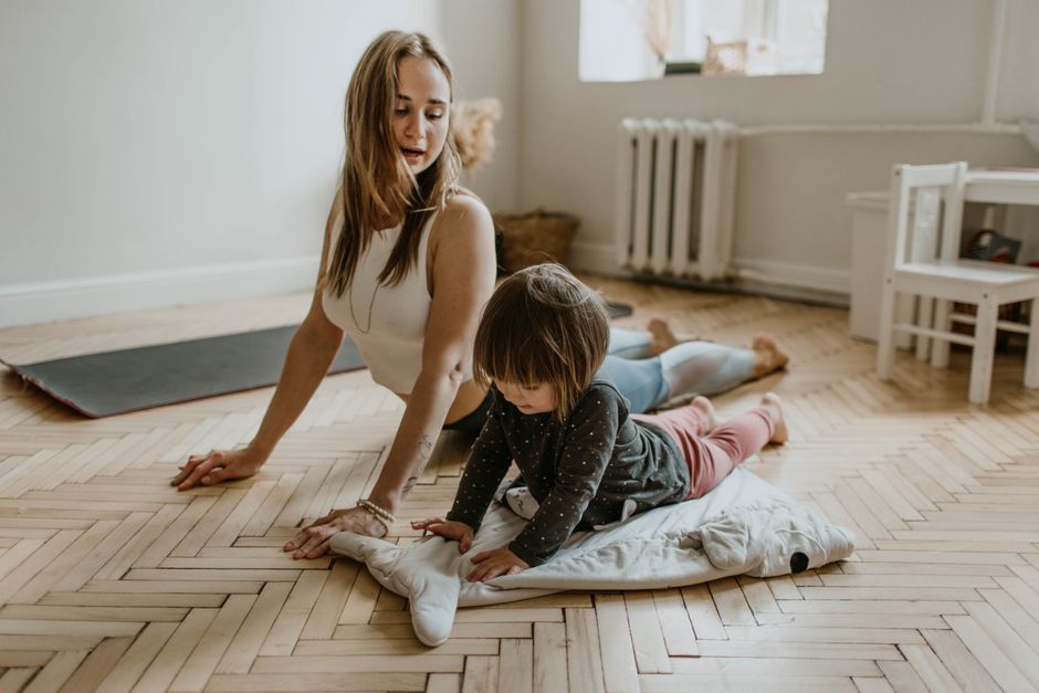 A mother and child practicing yoga together at home on a sunny day, fostering wellness and connection