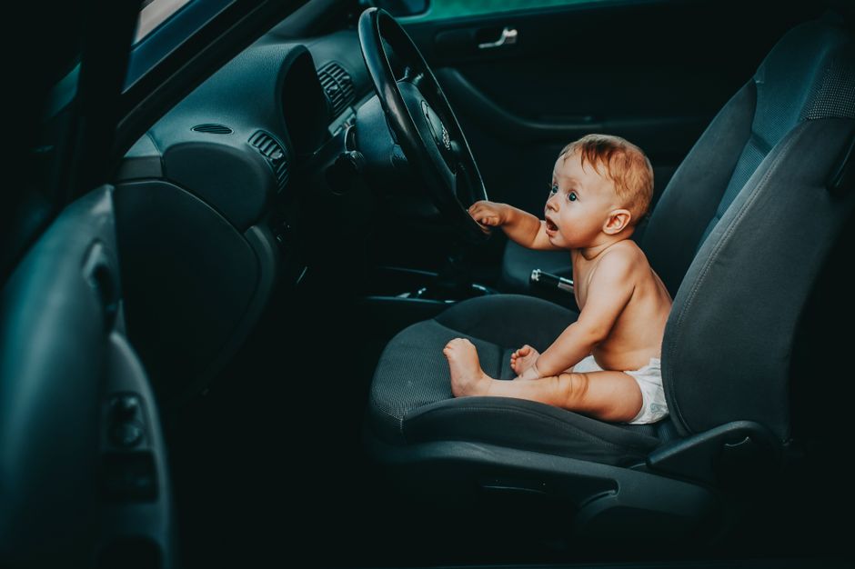 Cute baby sitting safely in a vehicle rear seat properly positioned for car safety inspection