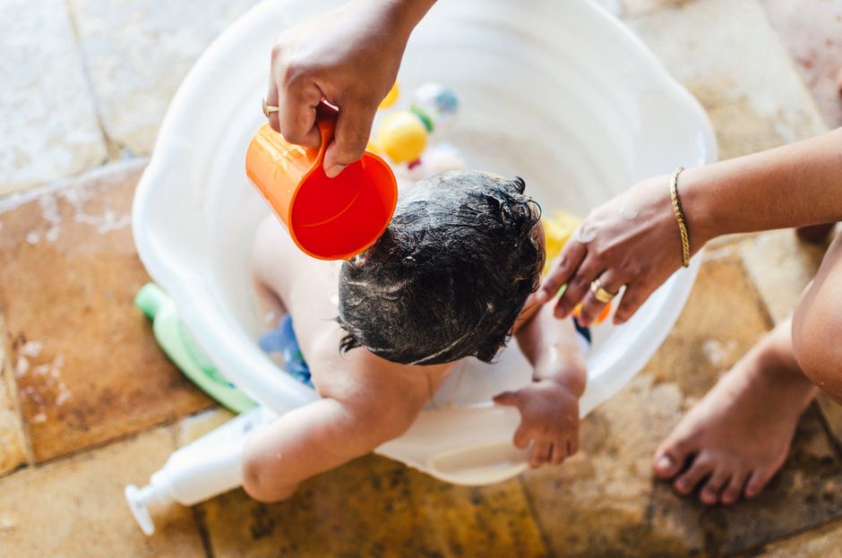 A caring parent bathing a baby in an outdoor setting. Playful and warm moment