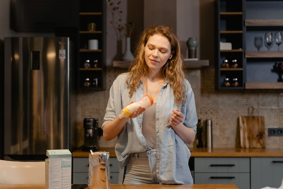 A mother preparing a baby bottle in a cozy kitchen, focusing on care and tenderness