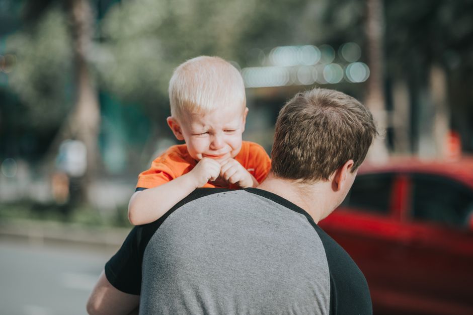 Father holding upset toddler in supportive calming embrace
