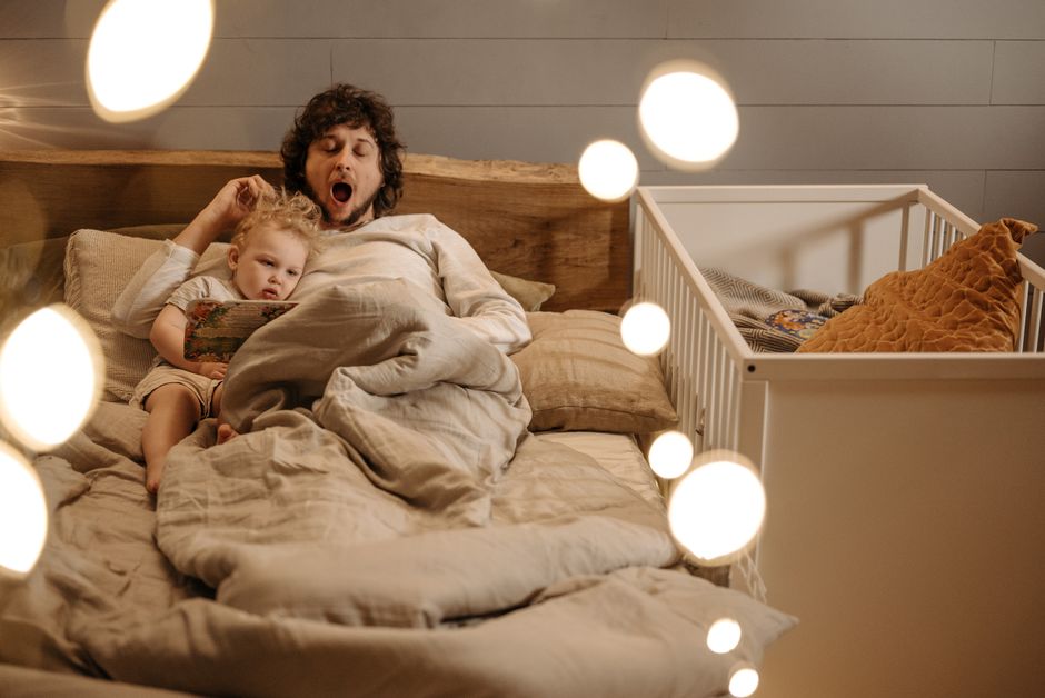 A parent reading a bedtime story to a calm toddler in a dimly lit bedroom