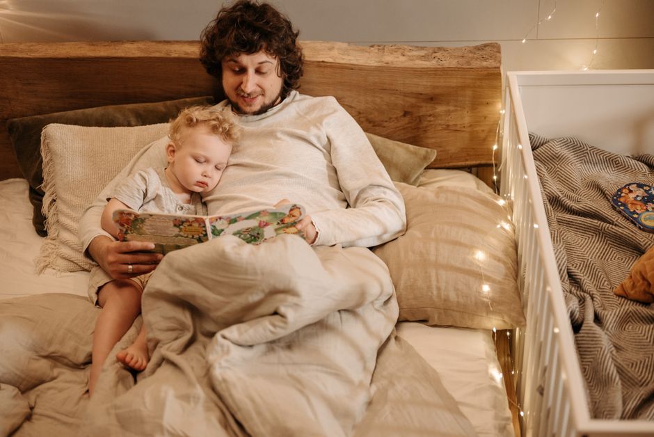 A father sharing a cozy bedtime story under soft amber light