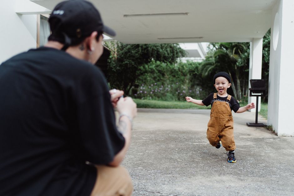 Father capturing a joyful moment as son runs happily in the garden