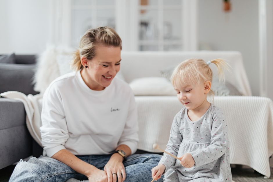 A joyful mother and daughter duo playing xylophone together in a cozy living room