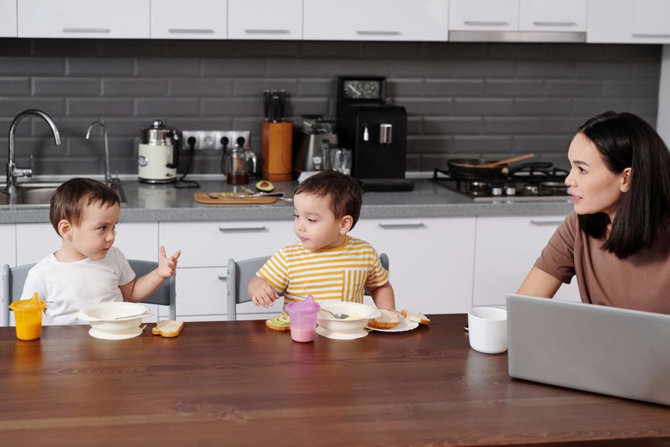Mother having breakfast with her young children in a bright kitchen