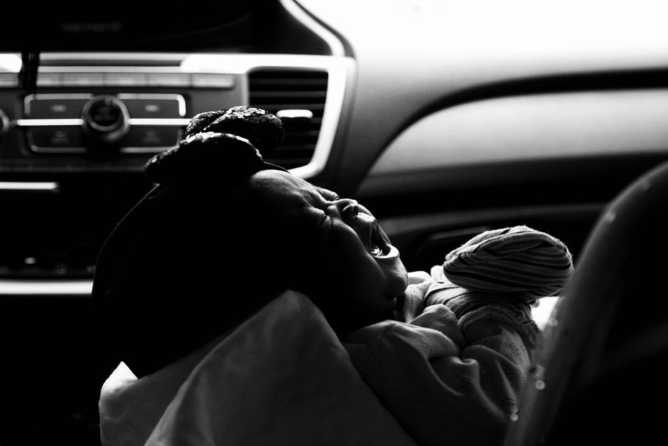 A toddler experiencing big emotions while being strapped into a car seat