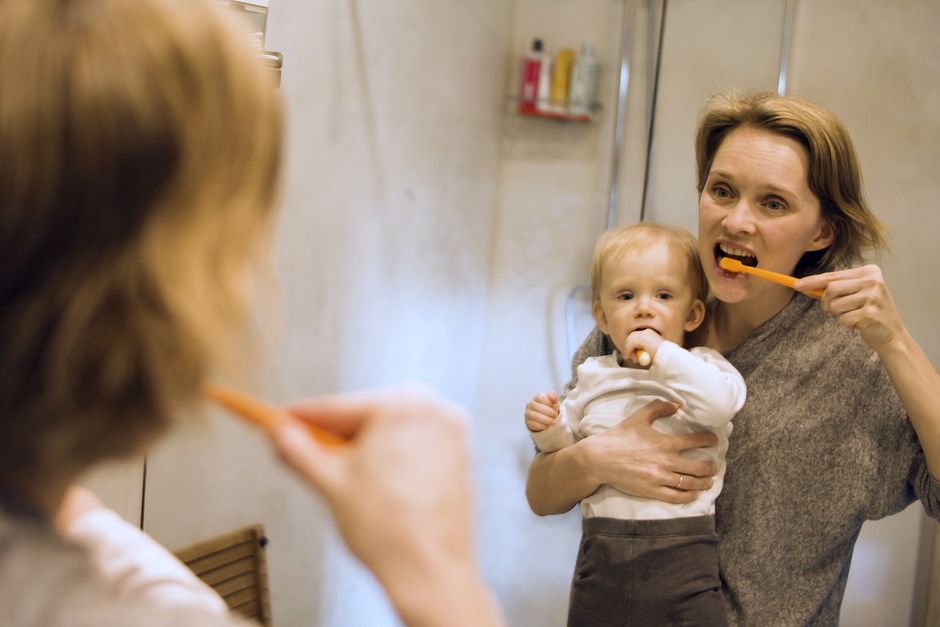 Mother and toddler brushing teeth together