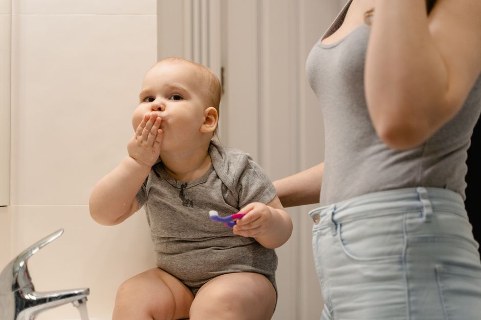 Happy toddler holding toothbrush with parent