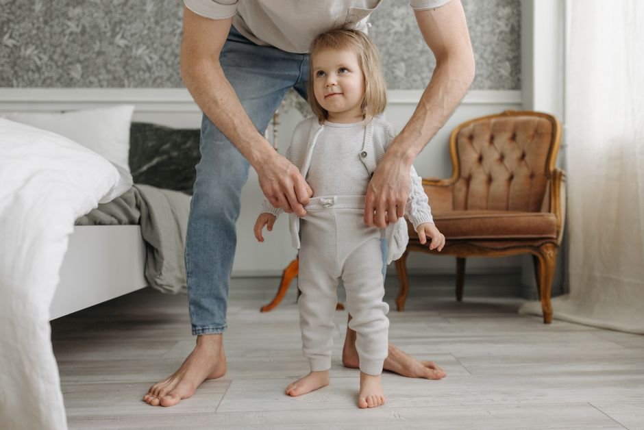 Father helping toddler get dressed comfortably in the morning