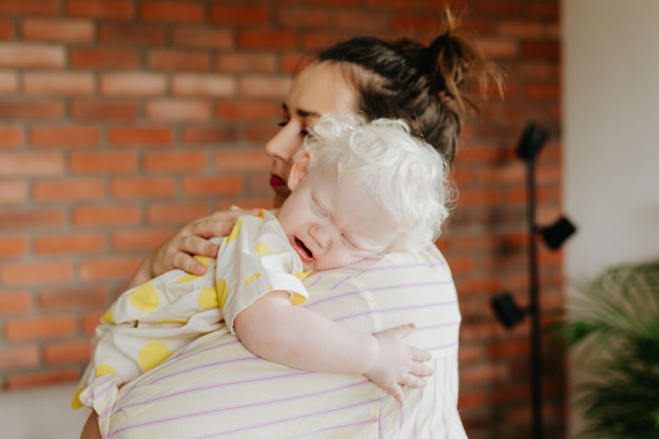Patient mother gently holding and co-regulating with her emotionally overwhelmed toddler