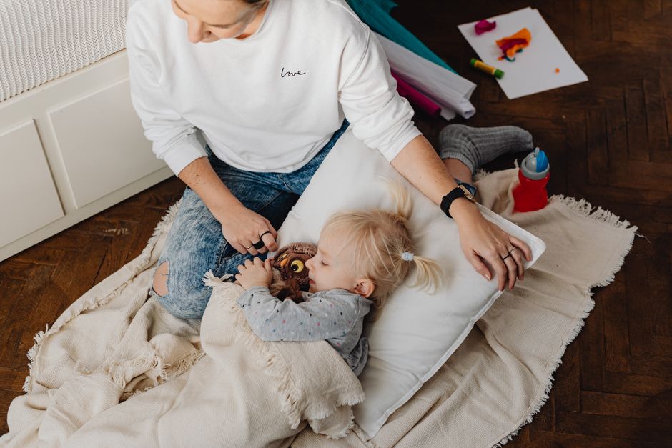 Patient mother gently guiding toddler on floor during frustration