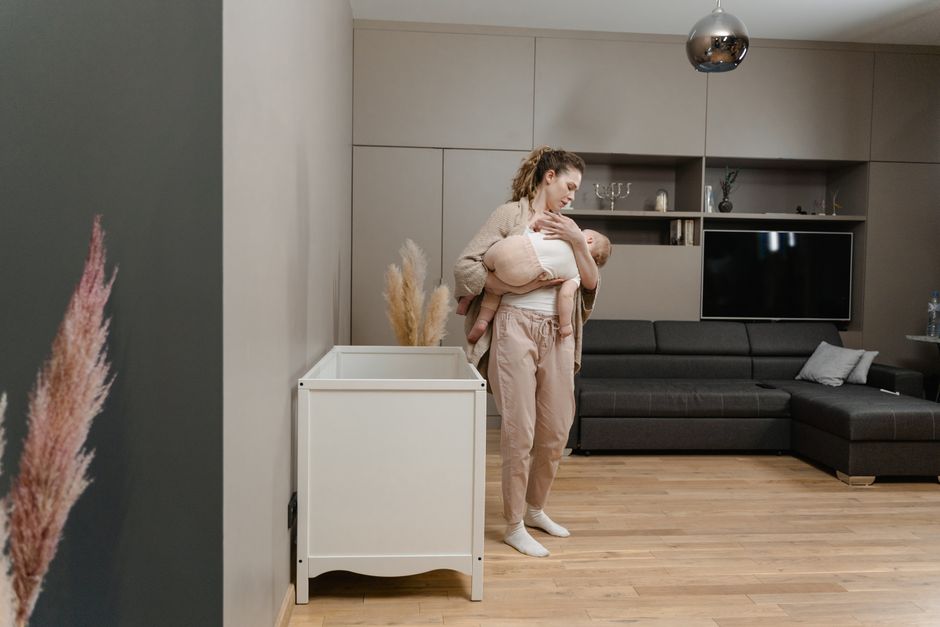 Smiling mother sitting close with connected toddler on floor