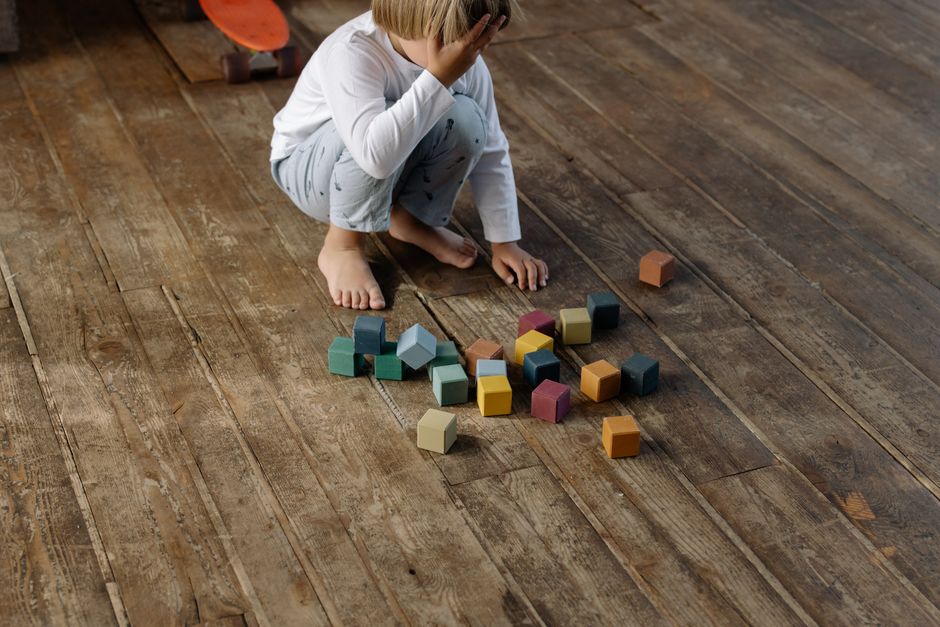 Child playing with colorful building blocks on the nursery floor