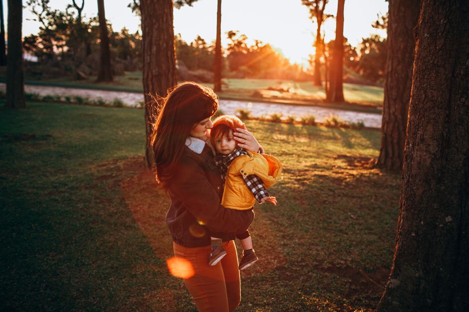 Mother holding toddler with warmth and connection in a park setting