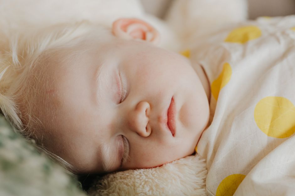Close-up of a sleeping baby with white hair and a polka dot blanket