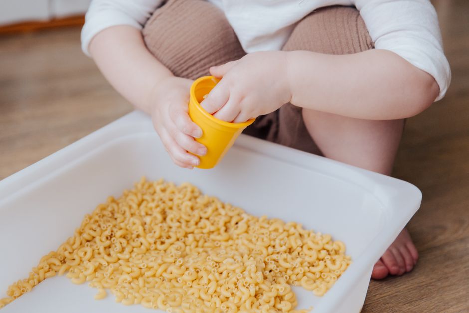Toddler safely engaging in dry sensory activity on the playroom floor
