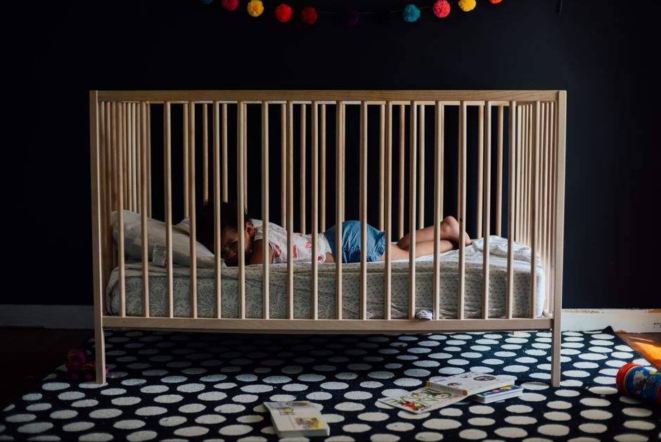 A peaceful infant sleeping safely on their back in an unweighted sleep sack within a bare crib