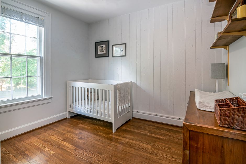 Serene baby room with crib, wooden flooring, and bright window light